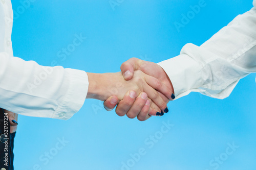 Crop of business partners hands making a deal in the office against blue background.