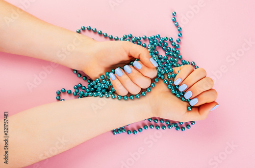 Stylish trendy female manicure. Beautiful young woman's hand with perfect blue manicure on pink background. Flat lay style.