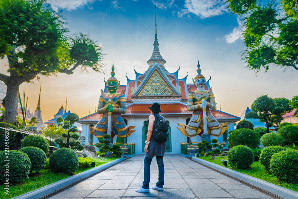 Obraz premium Traveler woman looking old temple in Wat Arun at evening sunset time, Popular famous landmark travel Bangkok Thailand, Tourist female on holiday vacation trip, Tourism beautiful destination place Asia