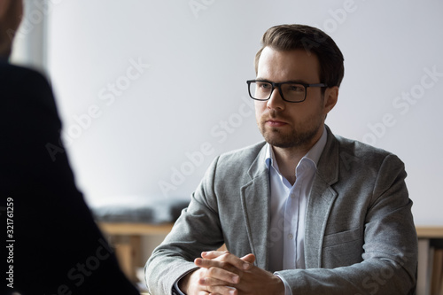 Canvas Print Serious businessman with clasped hands looking at opponent at negotiations