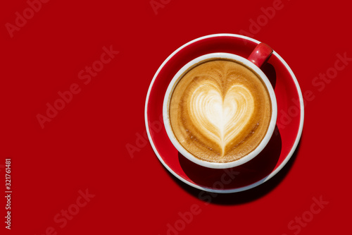 Top view Hot cappuccino coffee And with a cream like the heart in a red cup placed on red tone ground. isolated with clipping path. love and coffee concept for backdrop