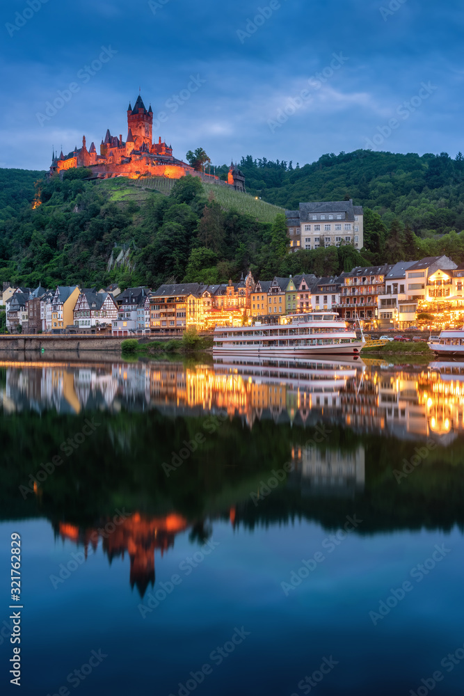 Obraz premium Cochem Castle, Germany, reflects in Moselle river with heritage European building and cruises during twilight