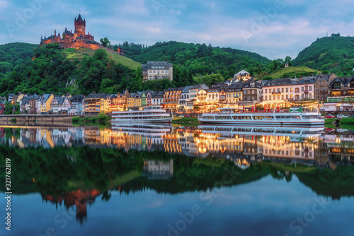 Cochem Castle, Germany, reflects in Moselle river with heritage European building and  cruises during twilight