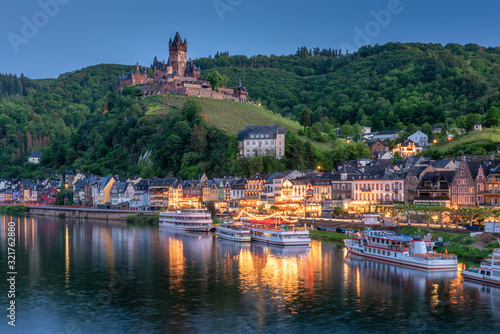 Cochem Castle, Germany, reflects in Moselle river with heritage European building and  cruises during twilight