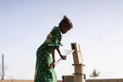 Fotografia Happy West African Women getting healthful Water in a typical village