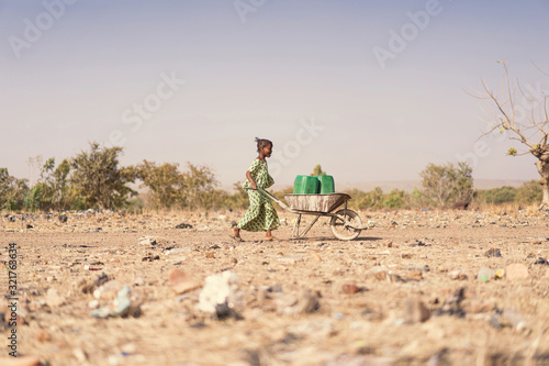Fotografía Tiny African Ethnicity Schoolgirl Engaged with nutritious Water for a lack of wa