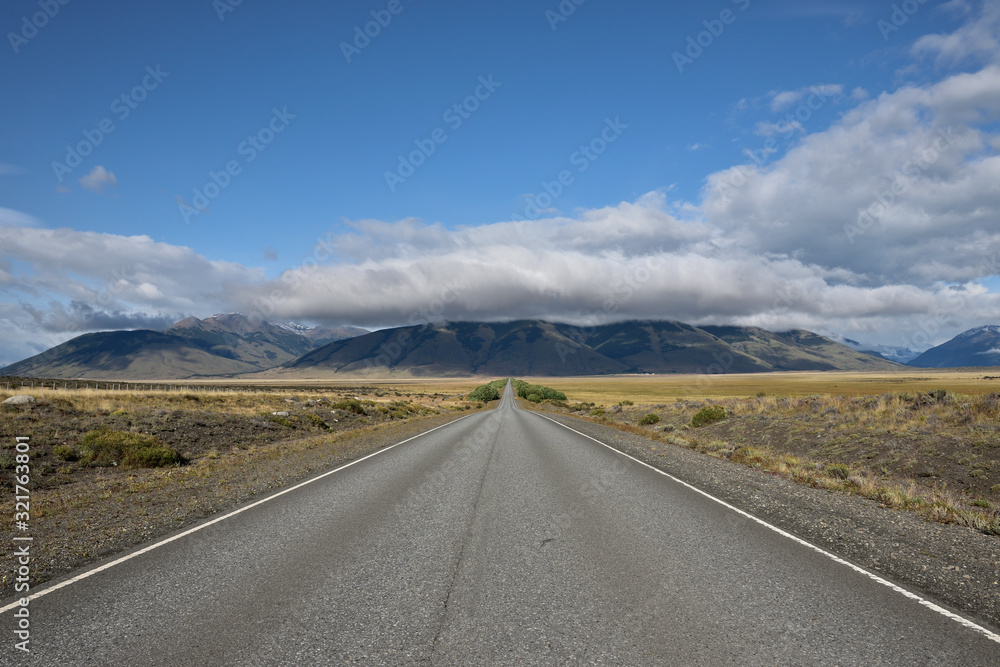 vista de carretera de asfalto con arboles montagnas y nubes de fondo