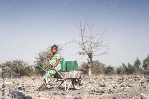 Valokuvatapetti Gorgeous African ethnic Infant with Fresh Water for an aridity concept