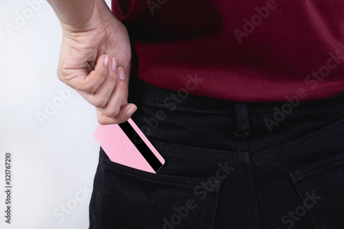 A girl wearing a red shirt while holding a credit card in her hand with a white background The concept is to put a credit card in the pants pocket.
