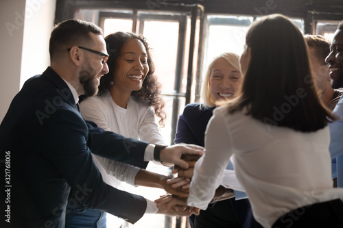 Multiracial entrepreneurs stacked hands together celebrating common victory