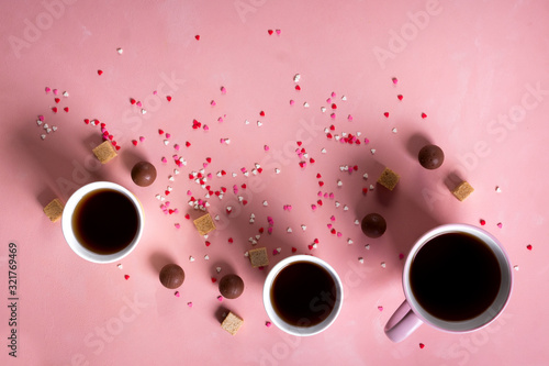 Coffee tea cups, sweets candy chocolate on pink hearts background. Valentines day 14 february minimal concept