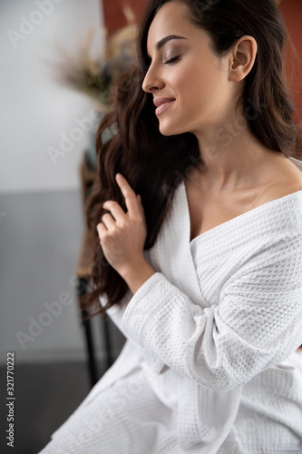 Attractive young woman touching her long curly hair
