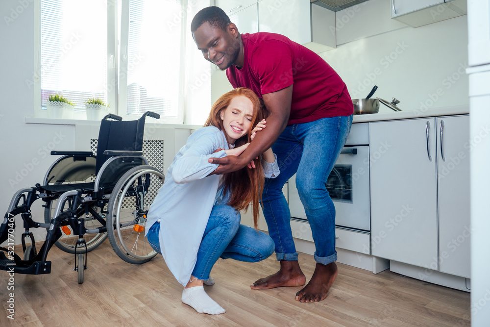 Young bearded handicapped redhaired ginger wife in wheelchair and her african american husband at kichen Young bearded handicapped redhaired ginger wife in wheelchair and her african american husband at kichen
