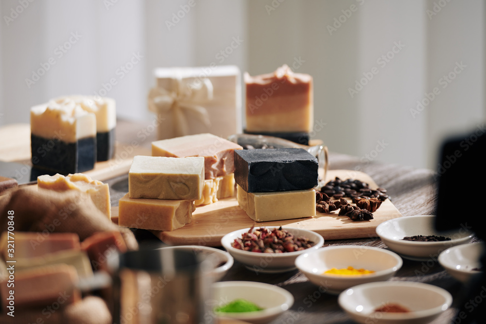 Various soap bars and bowls with natural ingredients on table in workshop