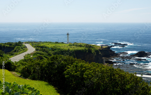 Solitary lighthouse on a rocky coast surrounded by green field