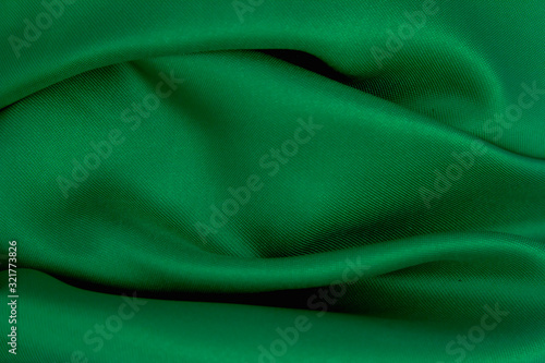 Green wrinkled fabric with wrinkles and waves, background and Wallpaper of crumpled tissue.