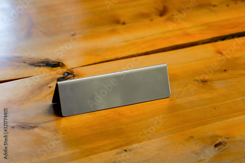 Blank metallic table top desk identification nameplate on a wooden desk