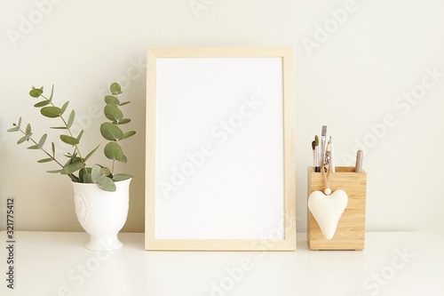 Minimal interior empty frame mock up on white table, eucalyptus and wooden decoration.       