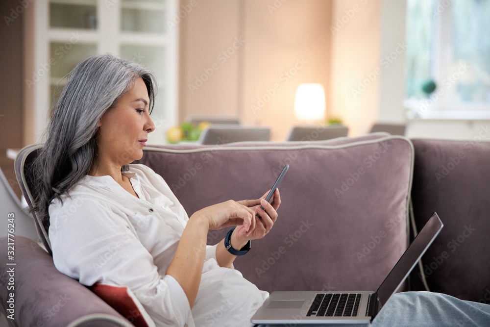 Serious lady with smartphone at home stock photo Serious lady with smartphone at home stock photo
