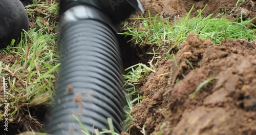 Worker digging out a trench to fit a new french drain pipe system in the ground