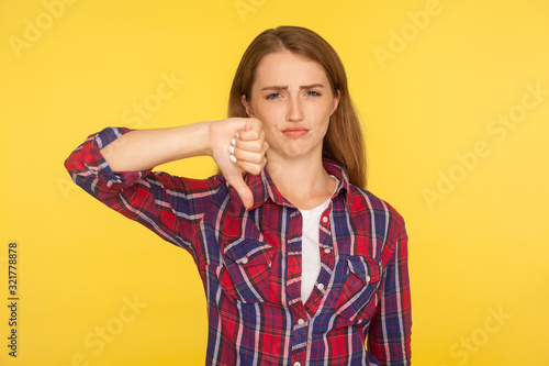 Fotografie Dislike! Portrait of dissatisfied unhappy ginger girl in red shirt showing thumb down gesture and looking displeased, negative feedback, disapproval sign