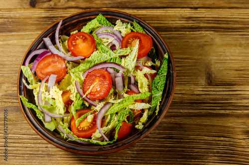 Healthy salad with savoy cabbage, cherry tomato, red onion and olive oil on wooden table. Top view