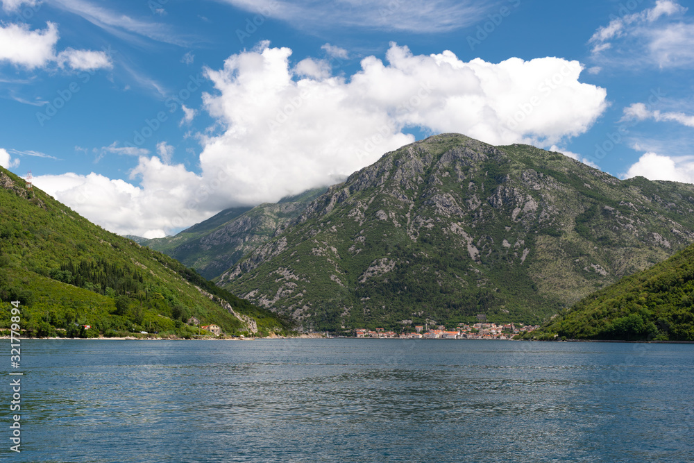 Landscape of mountains, sea and the small towns in the Boka Kotor bay of the Mediterranean Sea sunny day and white clouds. Montenegro.