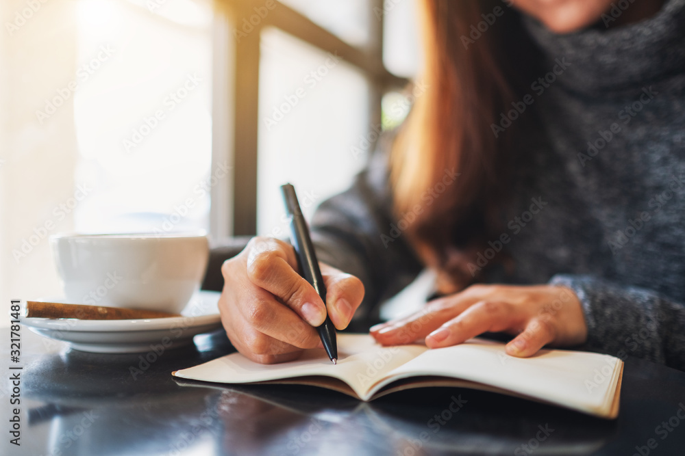 Closeup image of a woman writing on a blank notebook on the table Closeup image of a woman writing on a blank notebook on the table