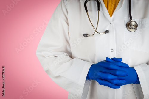Stethoscope and doctor hands on pink background. Selective focus and crop fragment