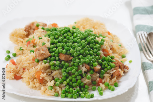 Rice with meat and vegetables close up on a plate on white background