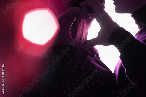 Silhouettes of the lips of lovers and a heart from the fingers of their hands