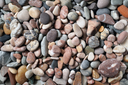 Gravel pattern of colored stones with shell. Abstract nature pebbles background.Small sea stones on the beach, vacation at sea. Top view 