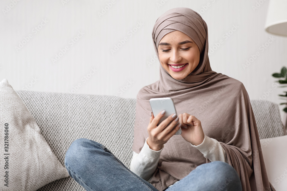 Happy arab woman scrolling social networks on smartphone at home Happy arab woman scrolling social networks on smartphone at home