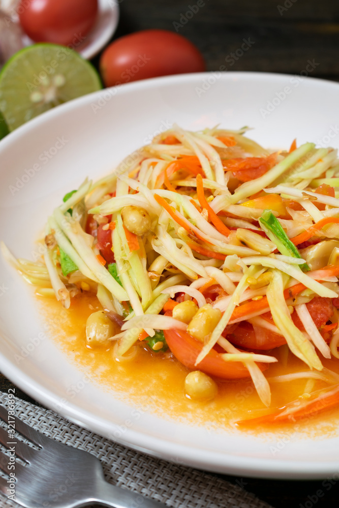 Papaya salad with chili and lemon in white dish on wooden table.(Som Tam Thai) Papaya salad with chili and lemon in white dish on wooden table.(Som Tam Thai)