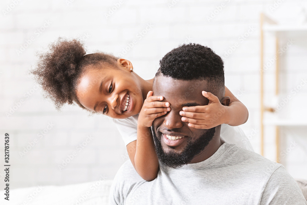 Fototapeta premium Cute little black girl covering her dad eyes
