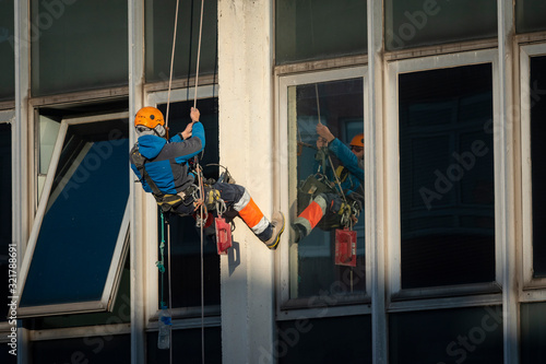 trabajador vertical colgado de una cuerda reparando una fachada ó obrero vertical reparando un edificio