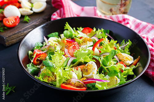 Fresh salad with vegetables tomatoes, red onions, lettuce and quail eggs. Healthy food and diet concept. Vegetarian food.
