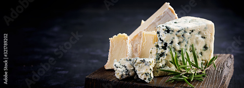 Cheese on wooden boards. Camembert and dorblu on wooden background. Dairy products. Banner