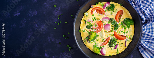 Omelette with broccoli, tomatoes and red onions in iron skillet. Italian frittata with vegetables. Top view, banner