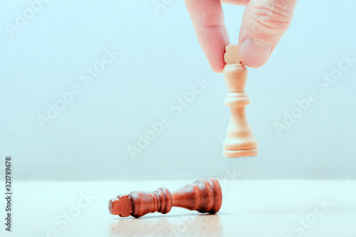 hand puts on the table a white piece of a chess kotol. on the table lies the defeated black king. business success concept.. photo