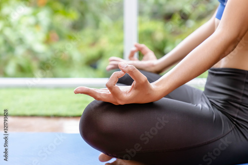 Attractive woman in sportware meditating in living room at home, closeup hand