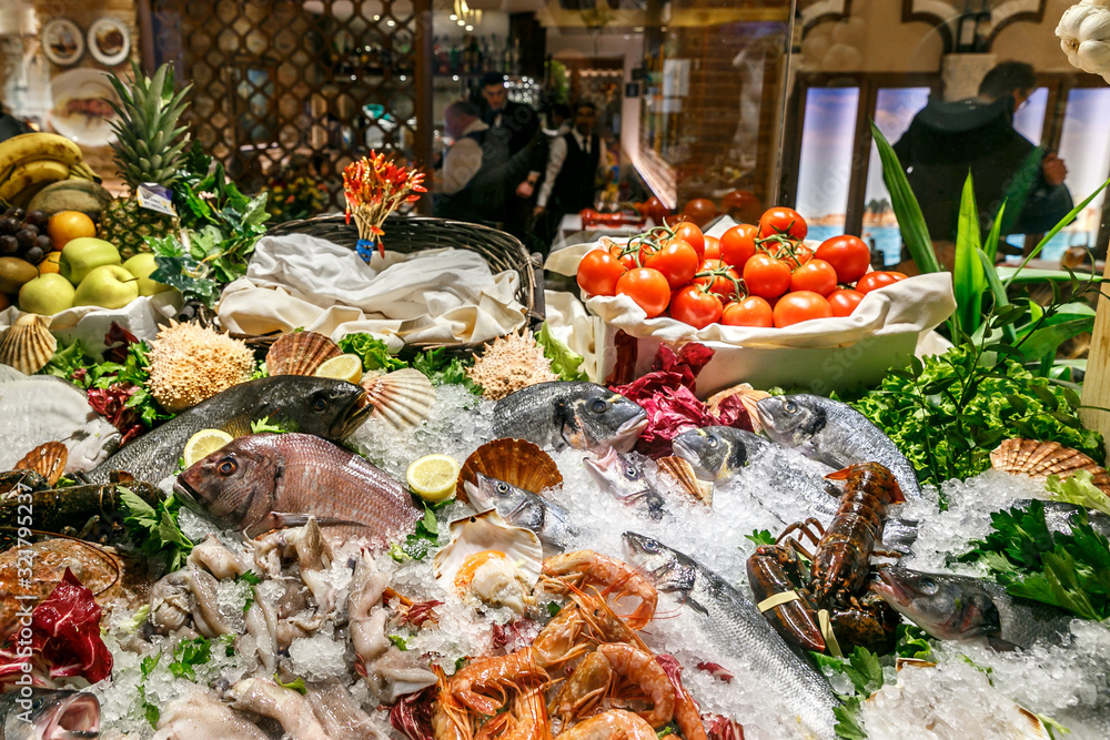 Obraz premium a variety of fresh seafood on a store’s sail. White-headed sea fish, shrimps, crabs, crayfish, mollusks lie on ice