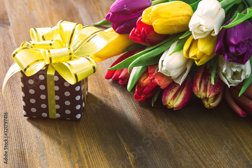 Multicolored tulips and a gift on the table for March 8