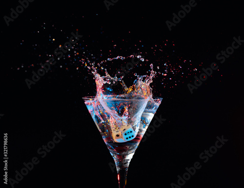 Dice fall in a glass of martini. Colourful cocktail in glass with splash.