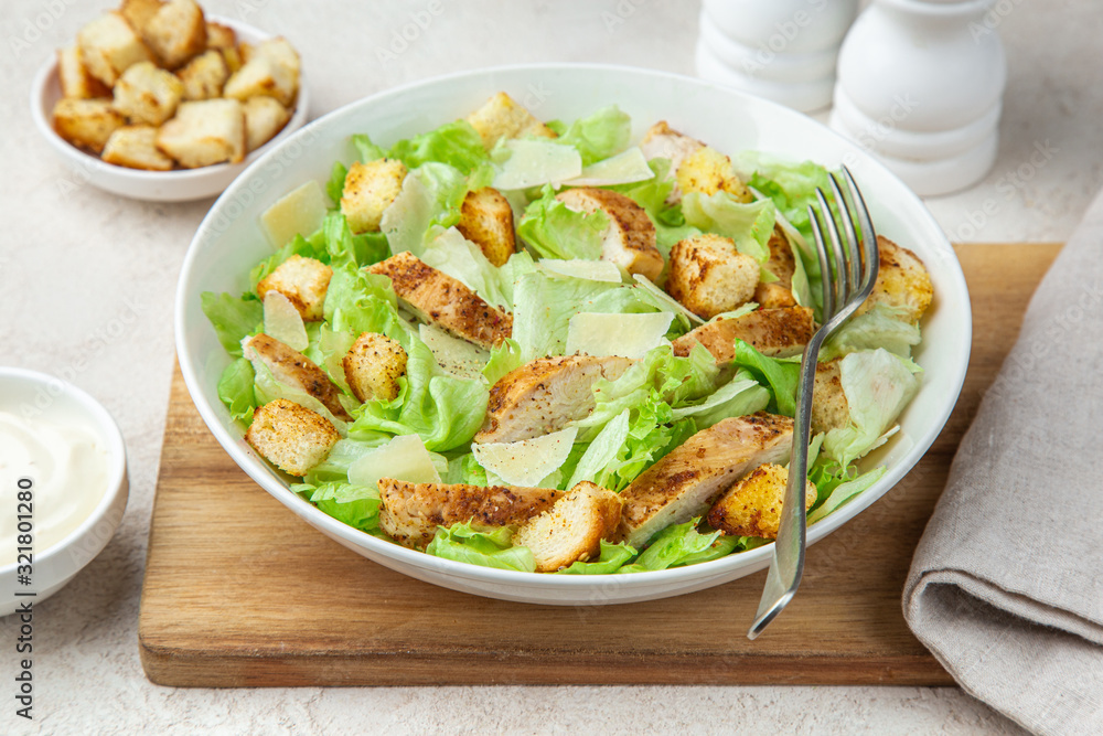traditional Caesar salad with lettuce, roasted chicken, croutons and cheese in white bowl traditional Caesar salad with lettuce, roasted chicken, croutons and cheese in white bowl