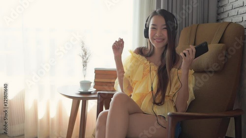 A happy young woman chair dances while listening to music through her headphones and smartphone. photo