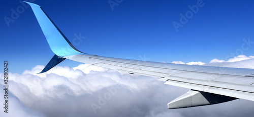 Langer Flügel eines Flugzeuges über flauschigen, weißen Wolken