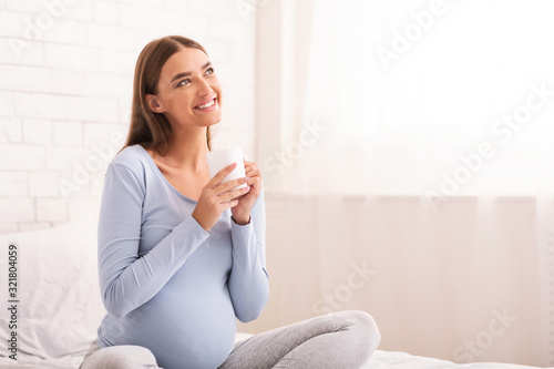 Cheerful Pregnant Girl Having Coffee Sitting In Bed Indoor