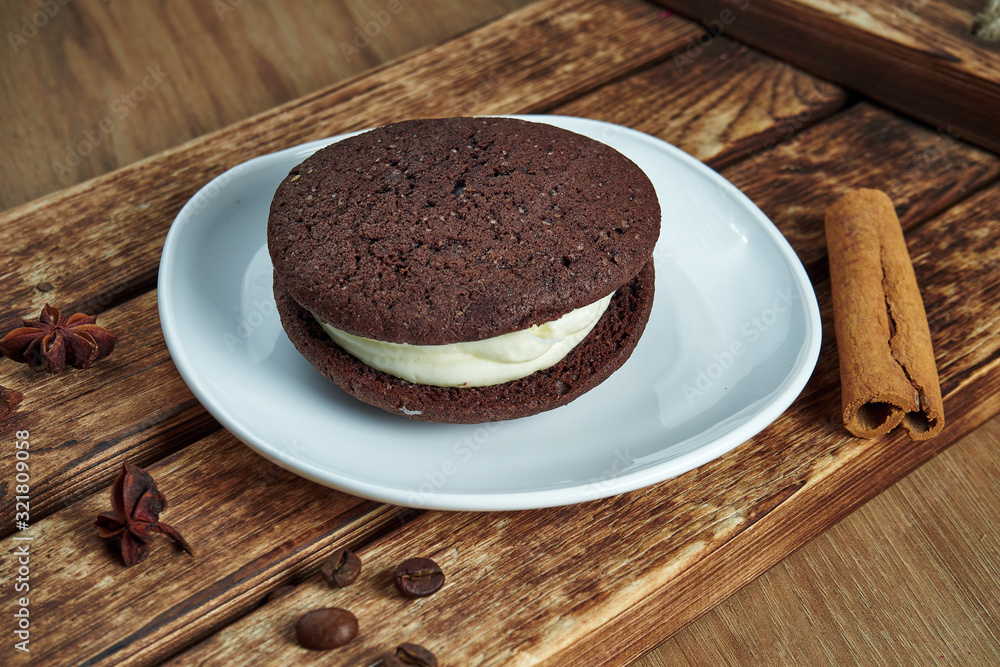 Sponge cocoa cookies with white cream inside on a white plate. Tasty dessert for coffee. Food photo flat lay. Bakery. Whoopie pies Sponge cocoa cookies with white cream inside on a white plate. Tasty dessert for coffee. Food photo flat lay. Bakery. Whoopie pies