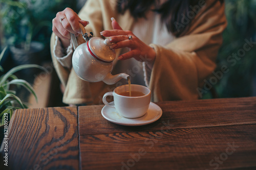 Female hands pouring tea into cup